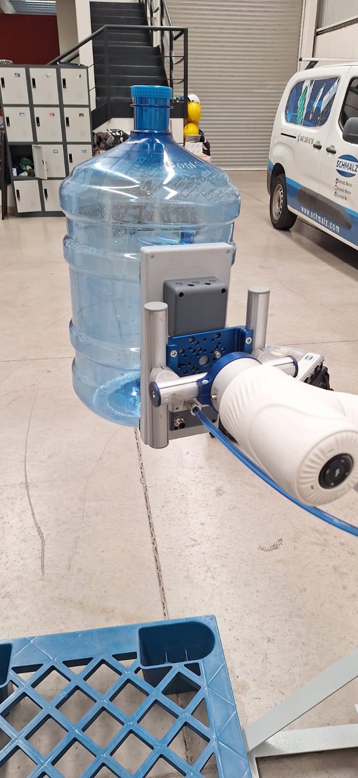 Cobot de 6 ejes con ventosa de vacío levantando un garrafón de agua sobre una tarima